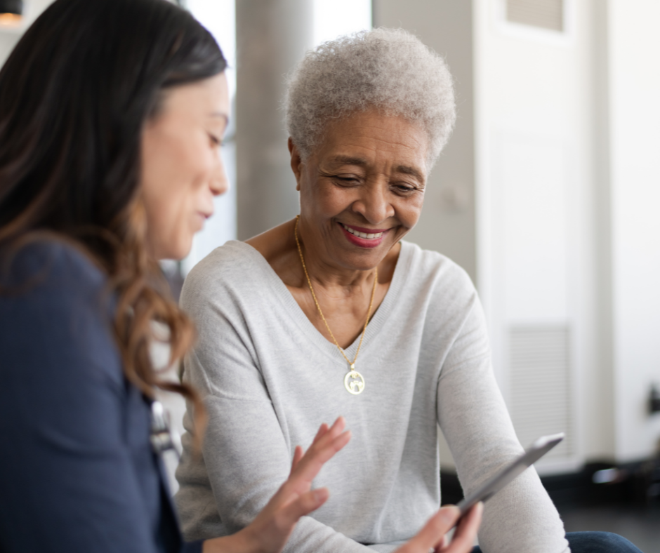 Younger Woman Talking to Older Woman and Showing Her Something on a Smart Phone.